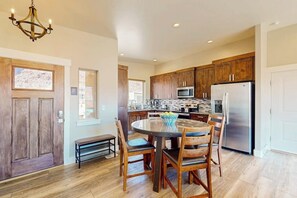 A kitchen with wooden cabinets, a stainless steel refrigerator, and a dining table with chairs. - Tranquil Home with Amazing Views and Great Location - Close to Arches National Park (Moab)