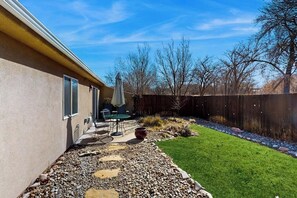 A backyard with a patio, outdoor furniture, a lawn, and a wooden fence. - Beautiful Dog-Friendly Home with Shared Indoor Pool, Yard, WiFi, and Fireplace (Moab)