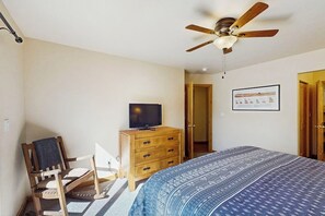 A bedroom with a bed, a wooden dresser, a television, a ceiling fan, and a door leading to another room. - Beautiful Dog-Friendly Home with Shared Indoor Pool, Yard, WiFi, and Fireplace (Moab)