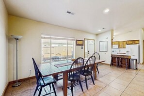 A dining area with a table and chairs, a floor lamp, and a kitchen area with cabinets and appliances. - Beautiful Dog-Friendly Home with Shared Indoor Pool, Yard, WiFi, and Fireplace (Moab)