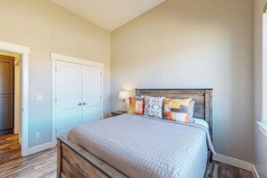 Quarto com cama, mesas de cabeceira e guarda-roupa.