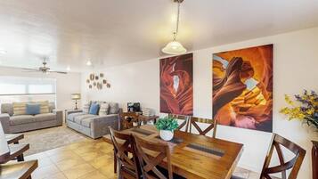 Ein Wohnzimmer mit einer Couch, einem Esstisch mit Stühlen und einem Deckenventilator.