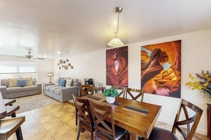 Ein Wohnzimmer mit einer Couch, einem Esstisch mit Stühlen und einem Deckenventilator.