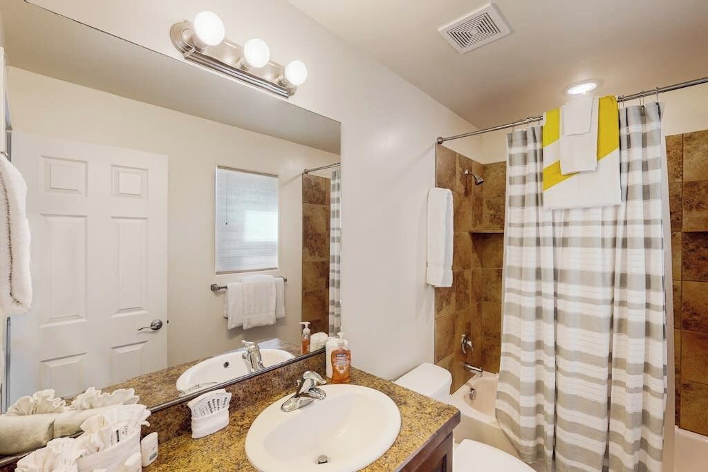 A bathroom with a sink, mirror, and shower curtain.
