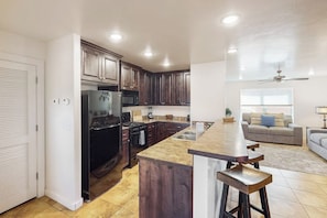 Eine moderne Küche mit dunklen Holzschränken, einem schwarzen Kühlschrank und einer Arbeitsplatte aus Granit.