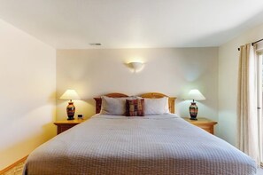 A hotel room with a large bed, two bedside lamps, a wall-mounted light, and a window with curtains. - Lovely Moab Townhouse with Shared Pool Near Arches National Park (Moab)