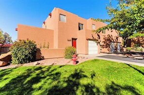 A two-story building with a red door and a garage. - Lovely Moab Townhouse with Shared Pool Near Arches National Park (Moab)