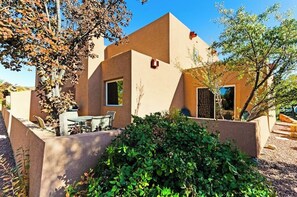 A modern building with a flat roof, large windows, and a patio area with outdoor furniture. - Lovely Moab Townhouse with Shared Pool Near Arches National Park (Moab)