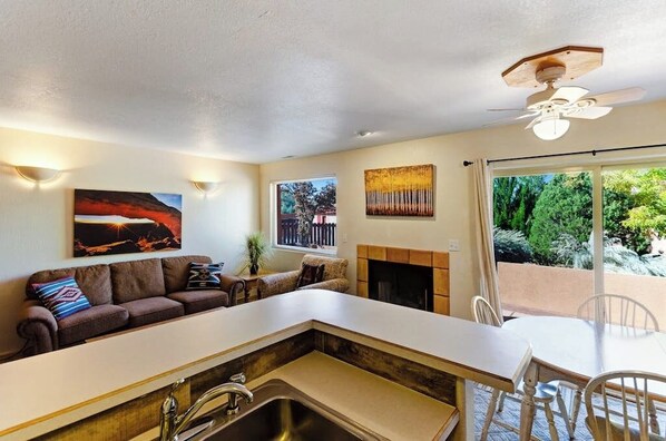 A modern kitchen with a built-in island, a dining area with a table and chairs, a sofa with cushions, and artwork on the walls. - Lovely Moab Townhouse with Shared Pool Near Arches National Park (Moab)
