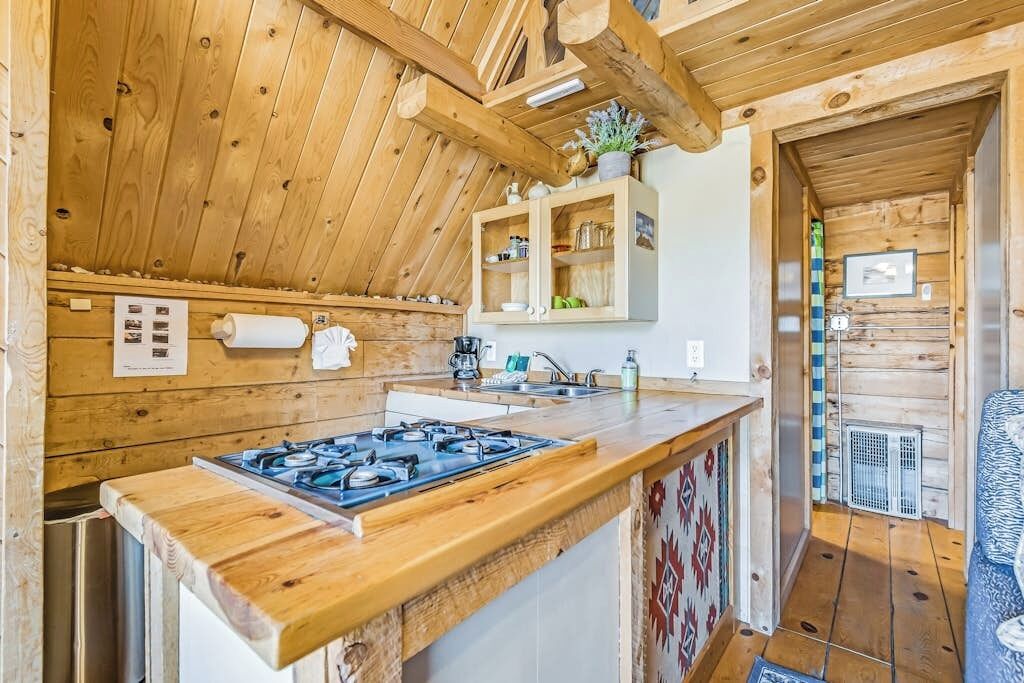 Een houten interieur met een keukenhoek, inclusief een gasfornuis, een gootsteen en kasten.