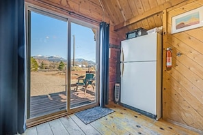 Une pièce dotée d’une porte-fenêtre coulissante donnant sur un espace extérieur avec vue sur les montagnes et une terrasse en bois.