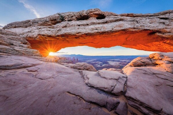 Una formación rocosa natural con una abertura iluminada por el sol.
