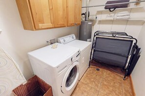 Ein kleiner Waschbereich mit Waschmaschine, Wäscheständer und einem Schrank zur Aufbewahrung.