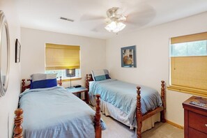 Ein Schlafzimmer mit zwei Holzbetten, einem Deckenventilator und einem Fenster mit Jalousien.