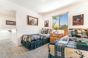 A bedroom with two beds, a dresser, and a window with a view. - Redesigned Red Rock Condo with Golf Course View, Patio, Fireplace, AC & Pool (Moab)