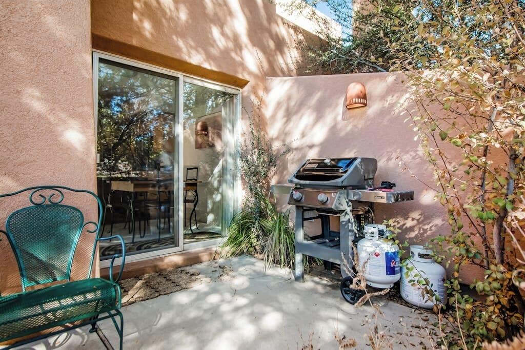 Eine Terrasse mit Grill, einem Stuhl und einer Glastür, die zu einem Raum führt.