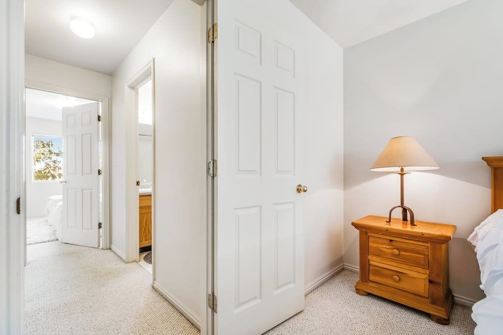 Une chambre avec une porte blanche, une table de chevet avec une lampe et un lit.