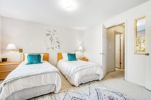 Ein Schlafzimmer mit zwei Betten, einem großen Wandbild und einer Tür zu einem anderen Raum.