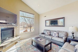 Ein Wohnzimmer mit Kamin, einer Couch, einem Couchtisch und einem Fernseher.