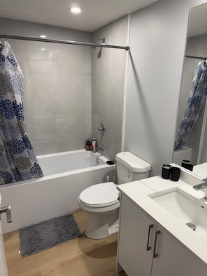 Een moderne badkamer met douche, toilet en wastafel.