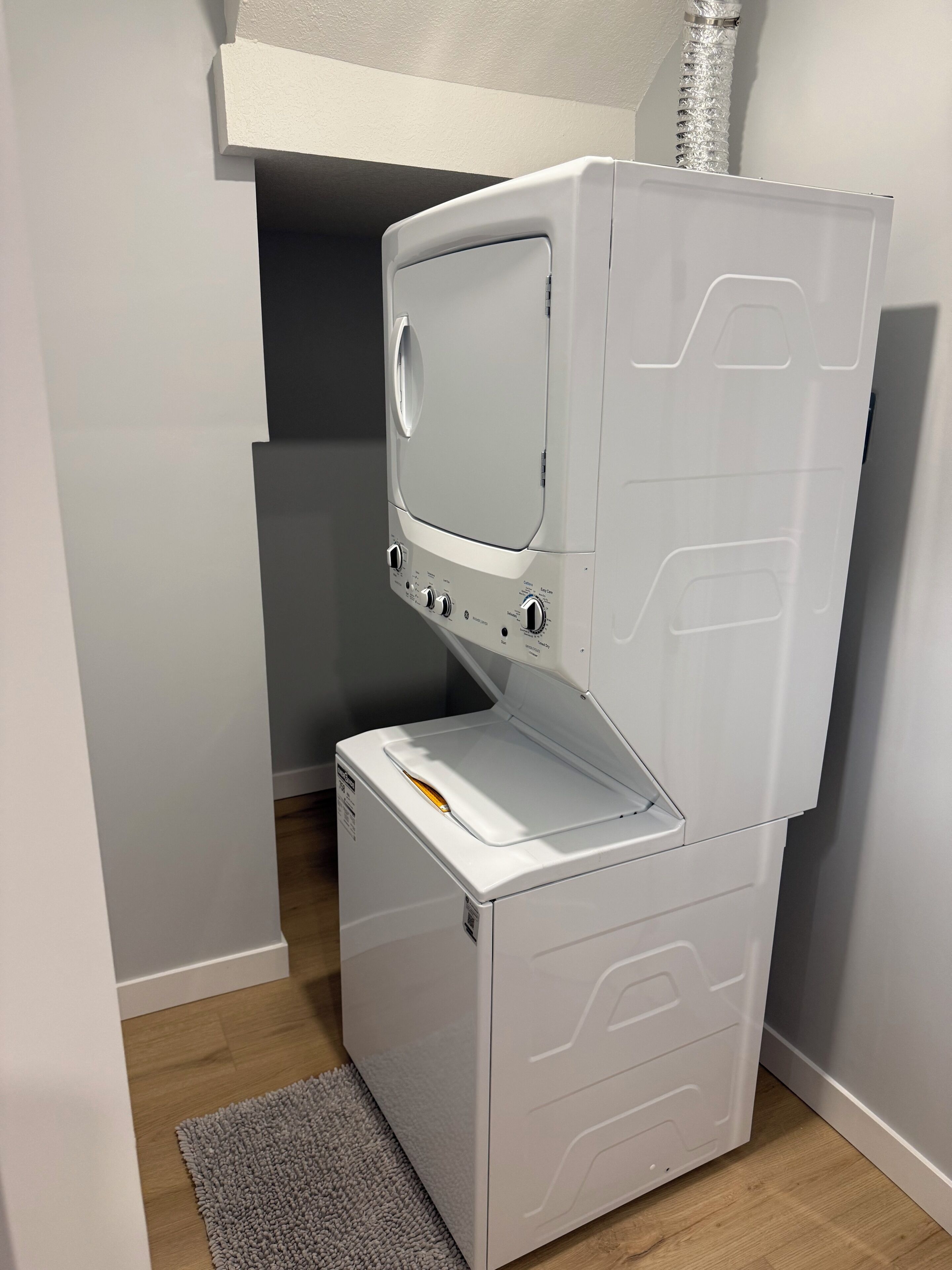 Un appareil compact, blanc, composé d’une machine à laver et d’un sèche-linge superposés, doté de boutons de commande et d’une petite fenêtre sur le dessus.