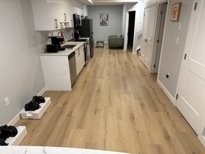 Et moderne køkken med hvide skabe, indbygget ovn og kaffemaskine.