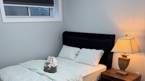 A bedroom with a bed, a nightstand, a lamp, a window, and a wall-mounted shelf. - Escape to a bright and spacious home tucked into a quiet, welcoming neighborhood (Edmonton)
