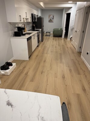 Eine moderne Küche mit weißen Schränken, einem Edelstahlkühlschrank und Holzboden.