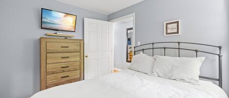 Ein Schlafzimmer mit einem Bett, einem Schminktisch, einem Fernseher und einer Tür.