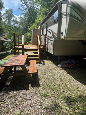 En campingvogn med et picnicbord og stole i en græsplæne.