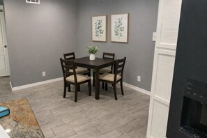 A dining area with a dark wooden table and chairs, a vase with a plant, and two framed botanical prints on the wall. - Sun Devil at 5th & Mill - 3BR - ASU, Mill Ave & Spring Training (Tempe)
