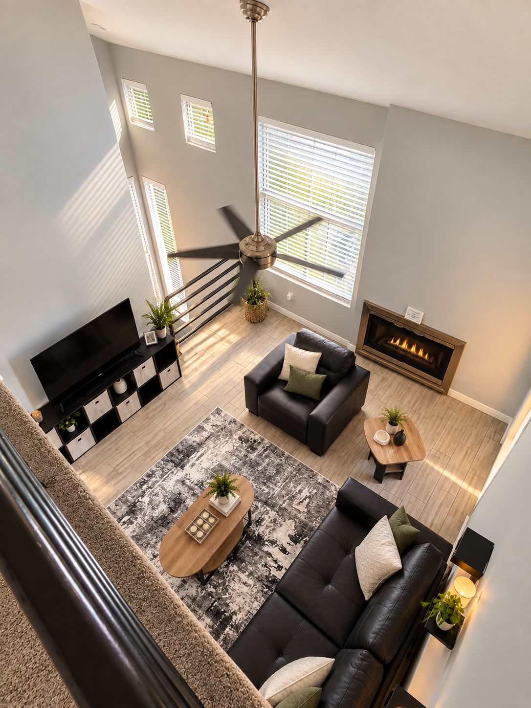 A modern living room with a black leather sofa, a wooden coffee table, a fireplace, and a television.