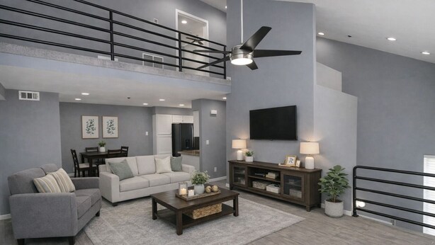 Una sala de estar amplia con techo alto, ventilador de techo, televisor de pantalla plana, sofá, mesa de centro y comedor con mesa y sillas.