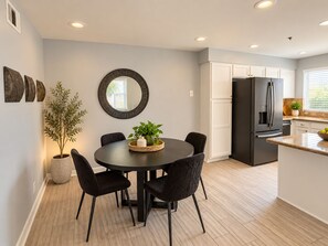 A modern kitchen with a black refrigerator, white cabinets, and a dining area with a round table and chairs. - Sun Devil at 5th & Mill - ASU, Mill Ave & Spring Training (Tempe)