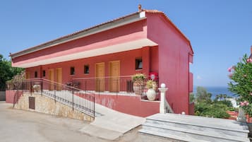 Un edificio rojo con tejado de baldosas, una escalera de piedra y vista al mar.