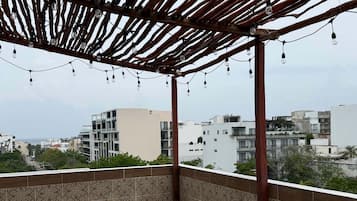 A covered outdoor area with a patterned floor, a wooden pergola, and string lights.