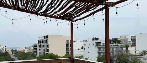 Un espacio al aire libre techado con suelo estampado, una pérgola de madera y luces colgantes.