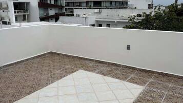 Une terrasse sur le toit, ornée de carreaux décoratifs, et entourée d’immeubles.