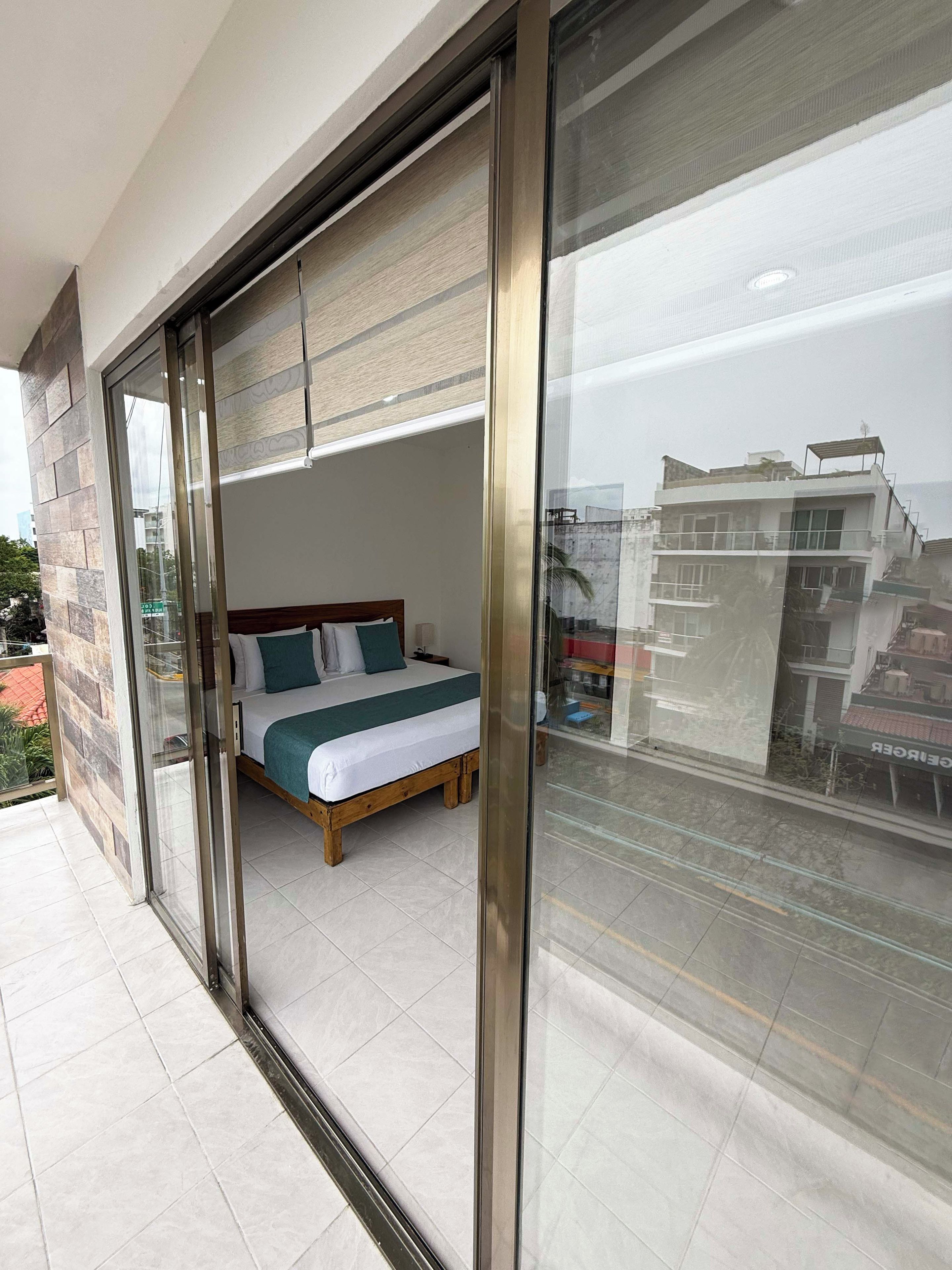 Un dormitorio con una cama, cabecera de madera y vistas a través de un ventanal.