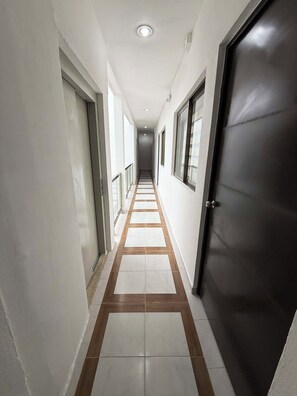 A corridor with a tiled floor, a door on the right, and windows on the left. - 27/27 Hotel Boutique (Playa del Carmen)