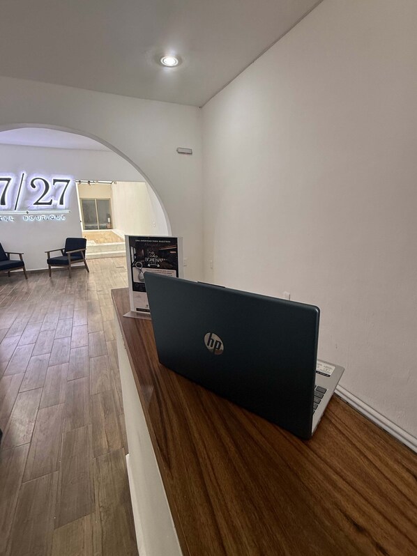 A hotel reception area with a wooden reception desk, an HP laptop, and a sign for '7/27 Boutique Hotel'. - 27/27 Hotel Boutique (Playa del Carmen)