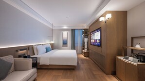 A hotel room with a bed, a sofa, a desk, and a TV. - Manxin Hotel Wuhan (WUHAN)