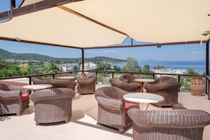Un área de estar al aire libre con mobiliario de mimbre y vista al mar.