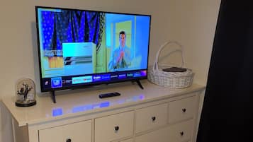 Ein Fernseher auf einer Kommode, zusammen mit einer Fernbedienung, einem Korb und einem dekorativen Gegenstand.