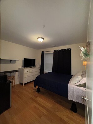 Ein Schlafzimmer mit einem Bett, einem Schreibtisch, einem Fernseher und einer Kommode.