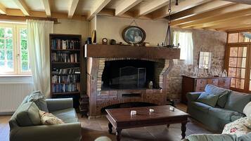 Een gezellige woonkamer met een open haard, een boekenkast en comfortabele zithoeken.
