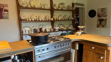 Une cuisine équipée d’une cuisinière, d’un four et d’étagères remplies de vaisselle.