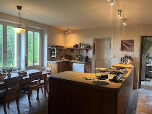 Une cuisine dotée d’un îlot central, de meubles en bois et d’une fenêtre donnant sur un espace verdoyant.