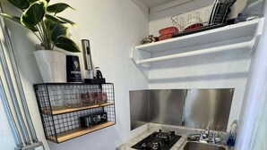 Cozinha compacta com fogão a gás, pia e lixeira.