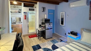 Quarto compacto com cama, mesa de jantar e cozinha compacta.